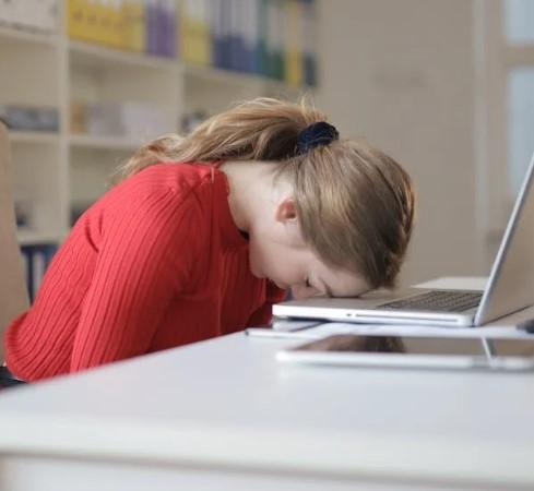 Woman with head resting on laptop looking tired