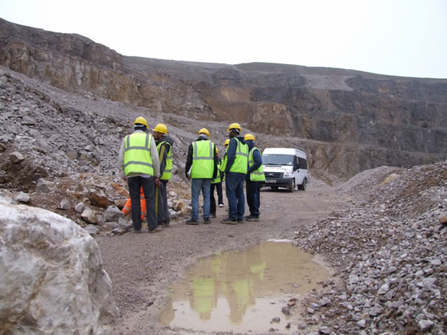 Students in high-vis jackets and hard hats in a quarry.