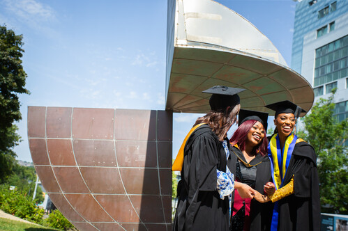 Graduating students underneath the University emblem statue