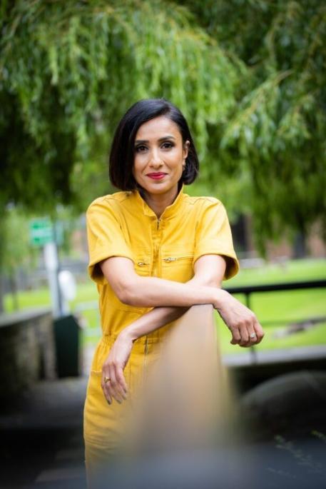 Chancellor Anita Rani, leaning on a rail for a picture.